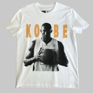 Camiseta blanca de algodón orgánico con imagen frontal de Kobe Bryant en blanco y negro y texto dorado, con logo de caravela en la parte trasera.